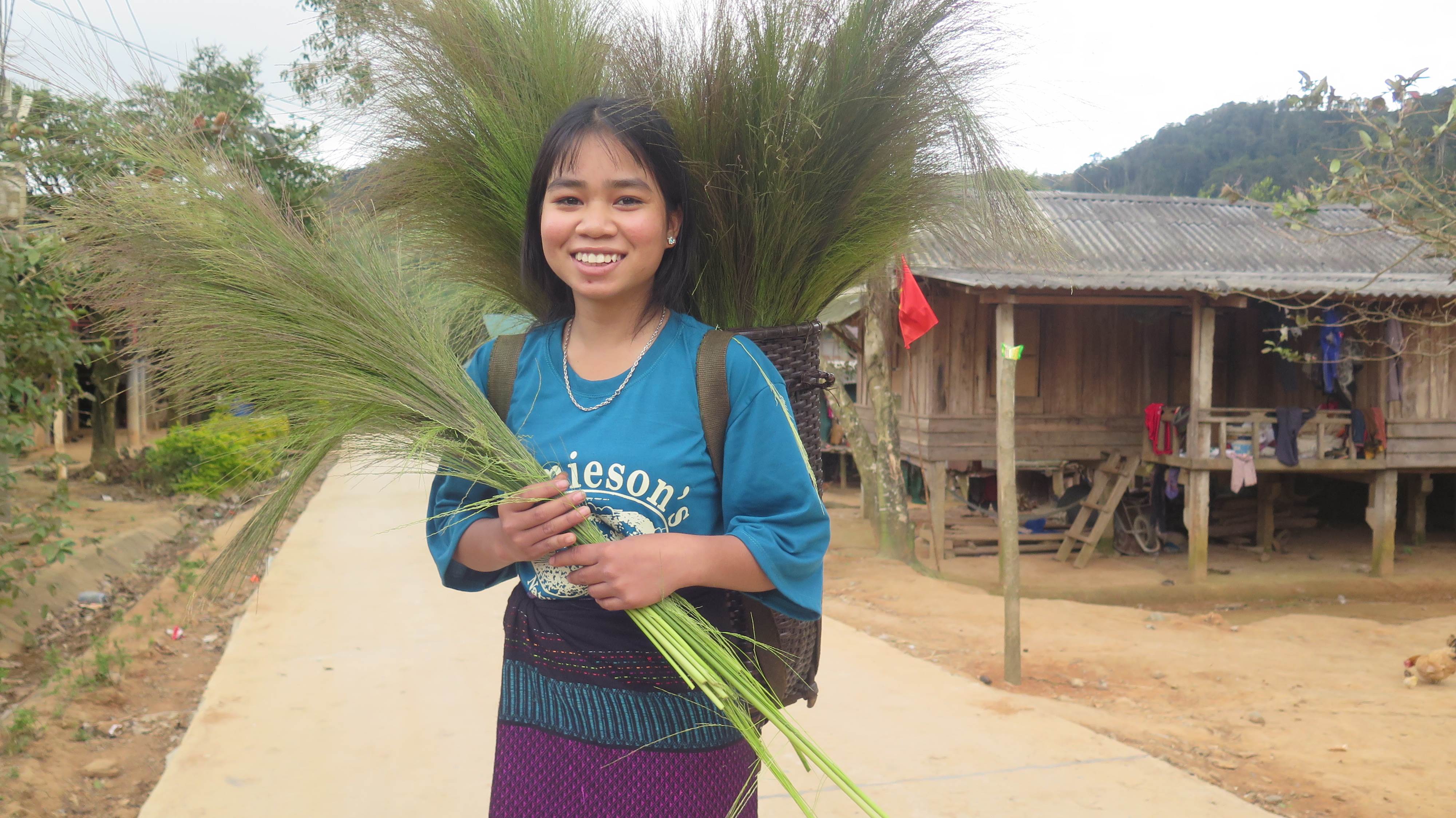 Girl from Vietnam holding some branches while smiling and looking at the camera