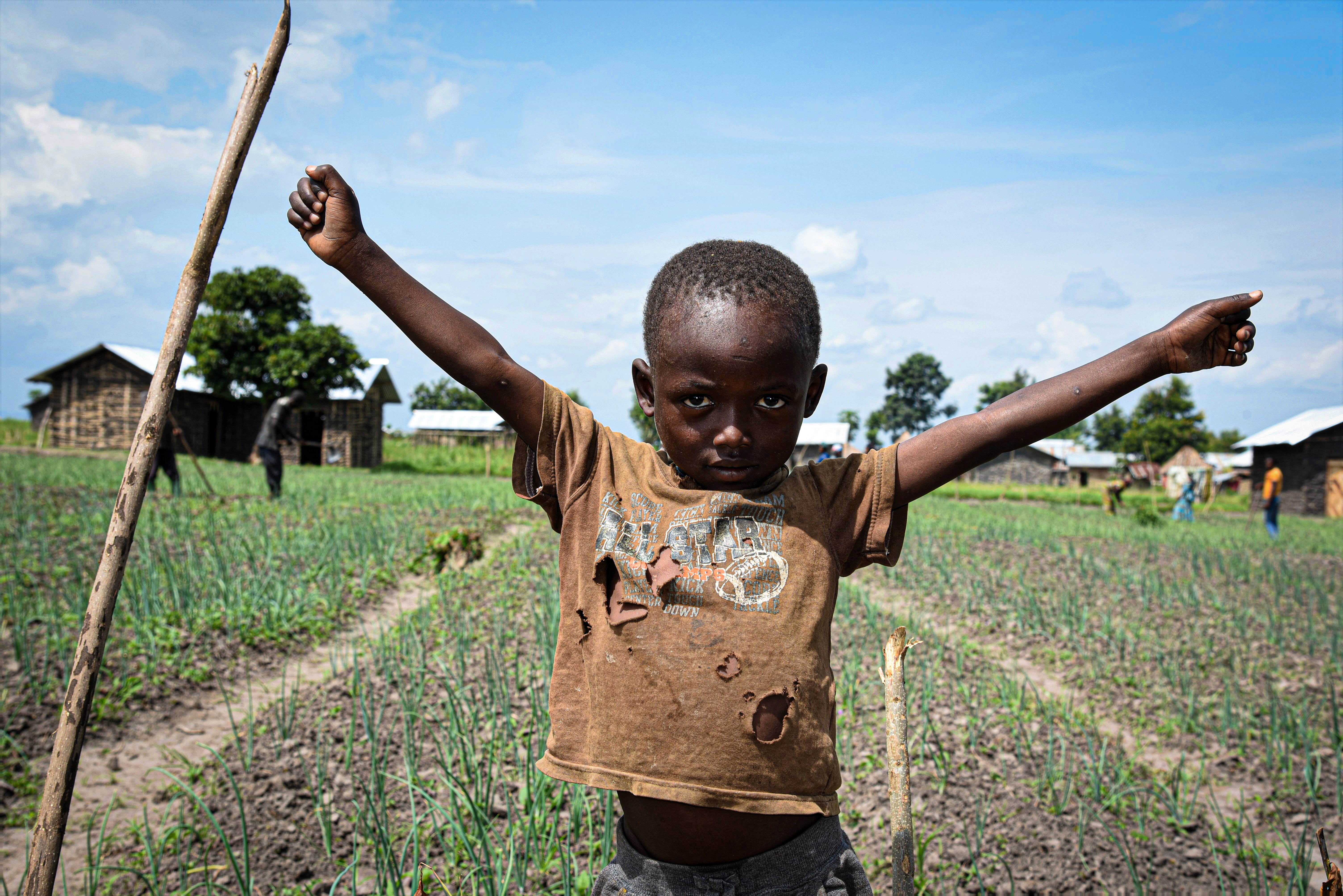 Boy from DRC cheering in front of a cabbage field.