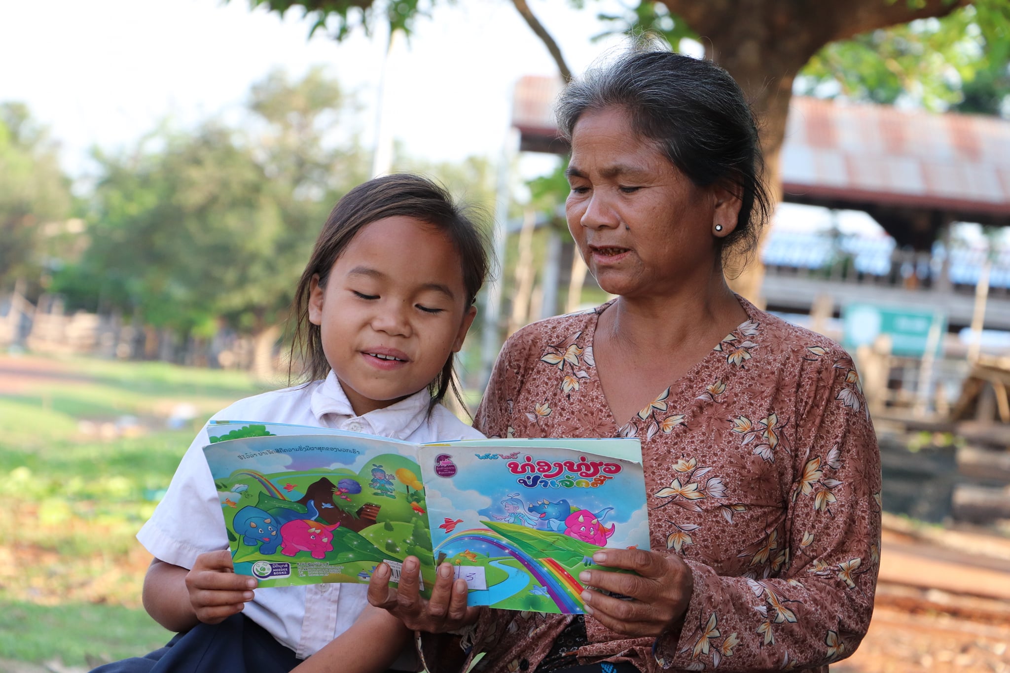 Girl from Laos reading a children's book with her grandmother