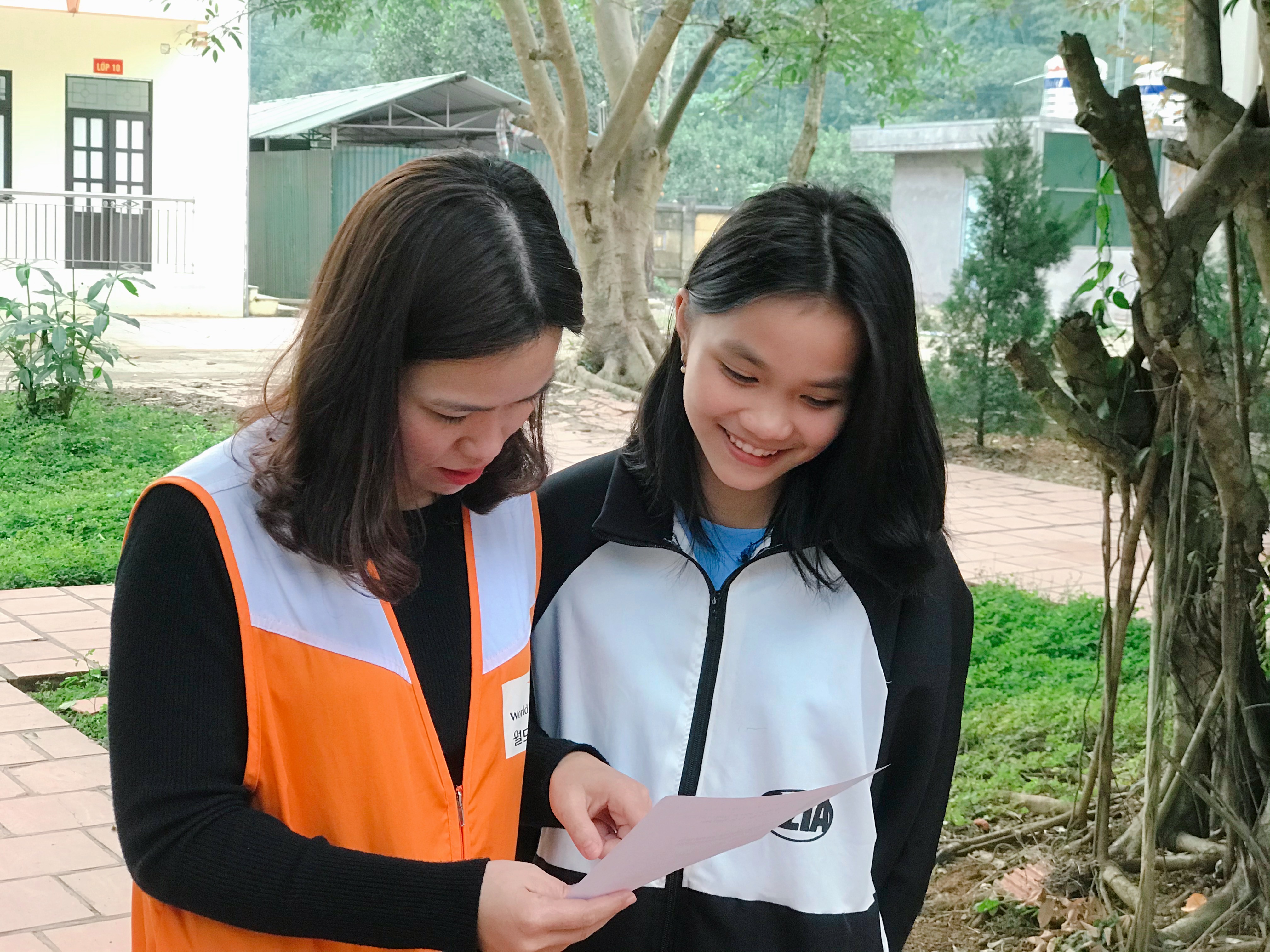 School girl from Vietnam reading her sponsor's letter with a World Vision representative.