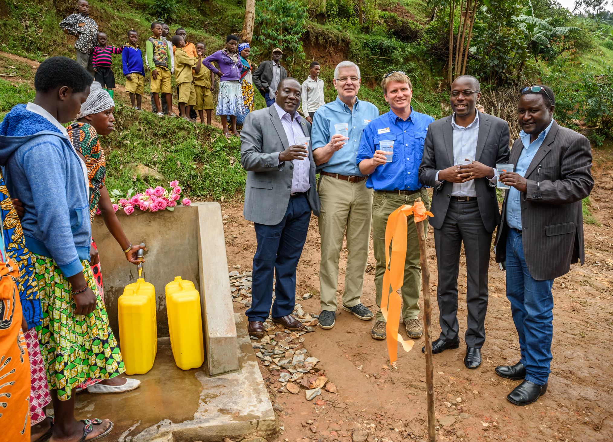 A group of people standing around a water distribution point in Rwanda