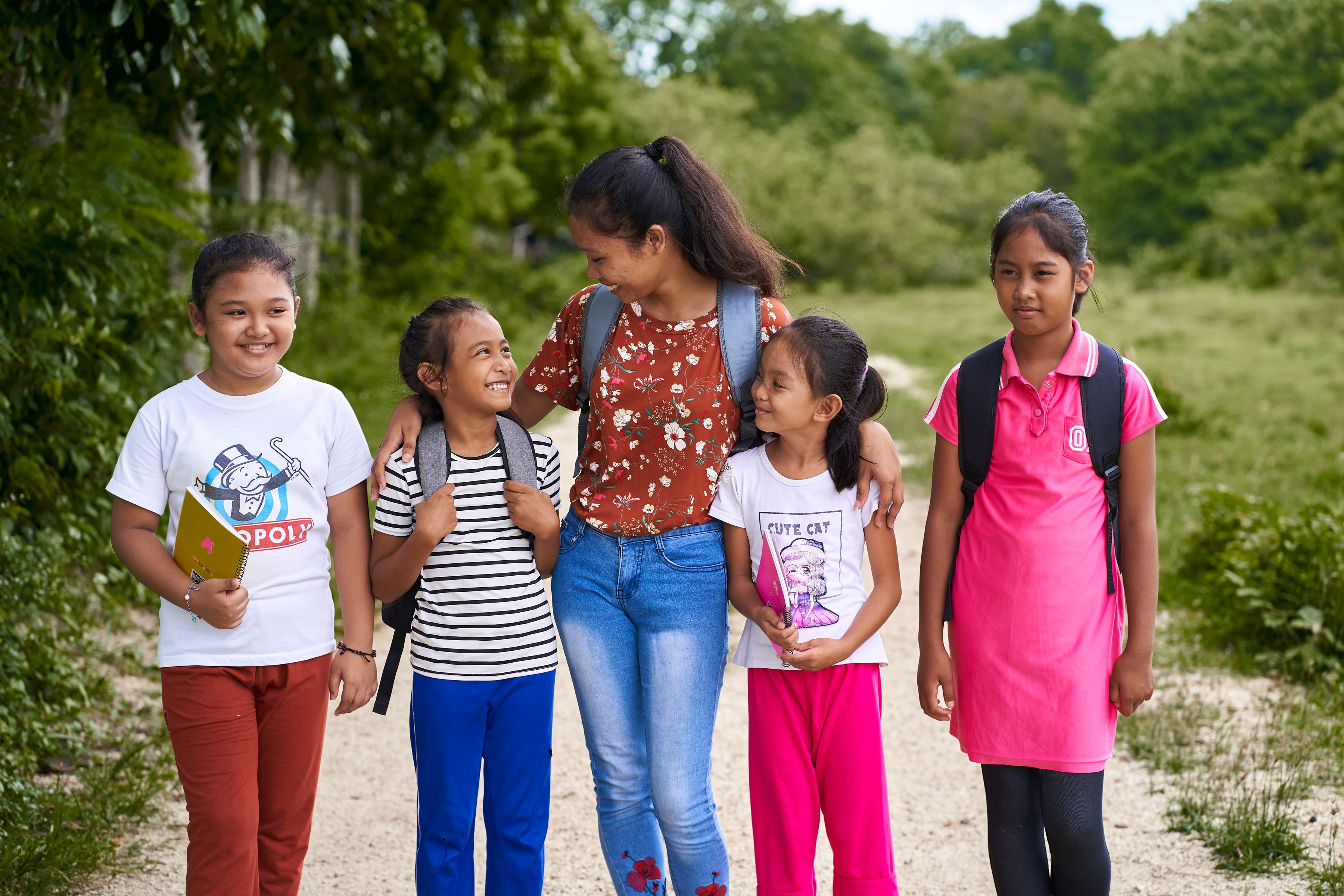 Five girls from the Philippines smiling and walking together in a park