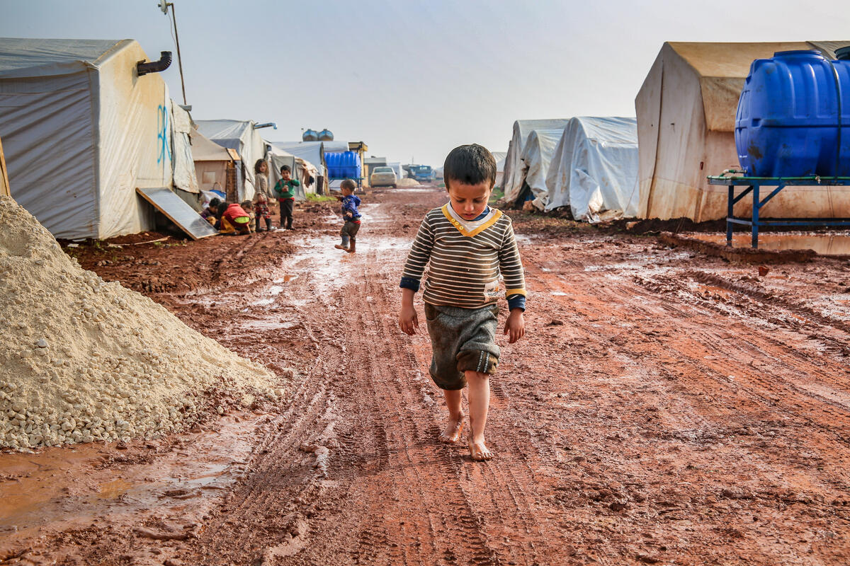 A boy walking the mud in an internally displaced camp in northwest Syria.