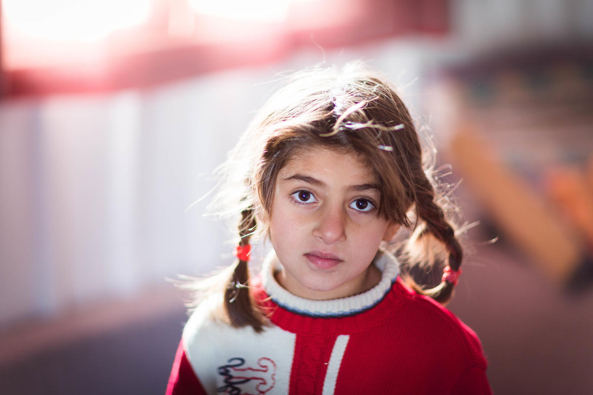Syrian refugee girl wearing a hoodie looking into the camera