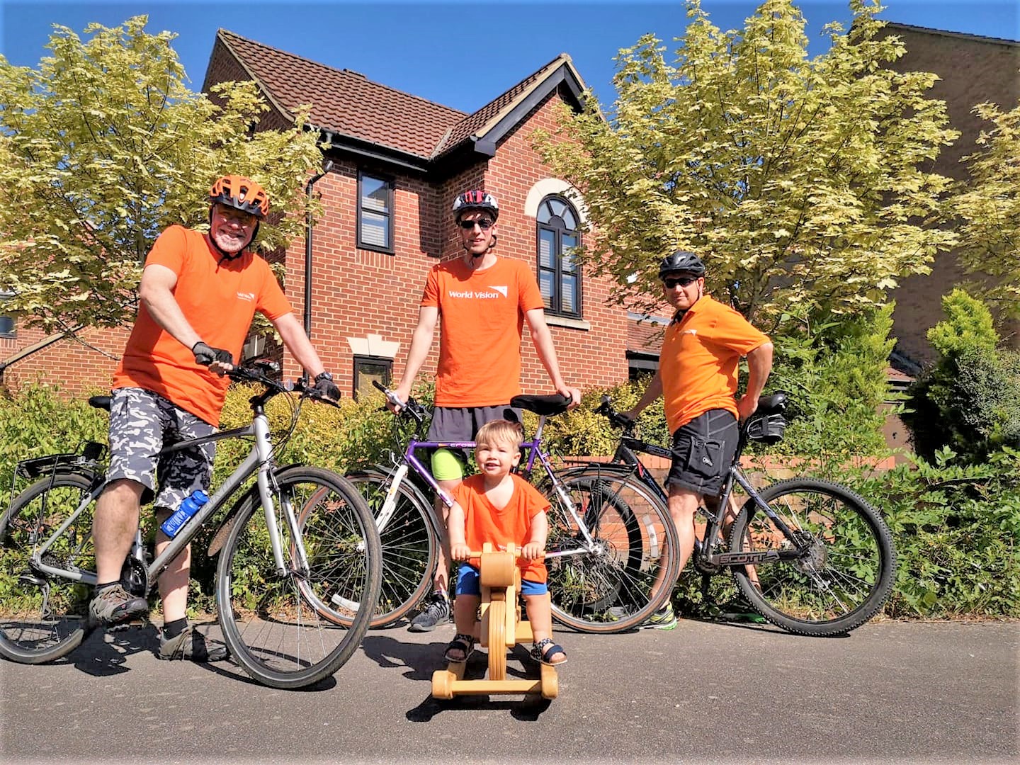 Family of four pose with bicycles in orange t-shirts to raise funds to protect children from coronavirus
