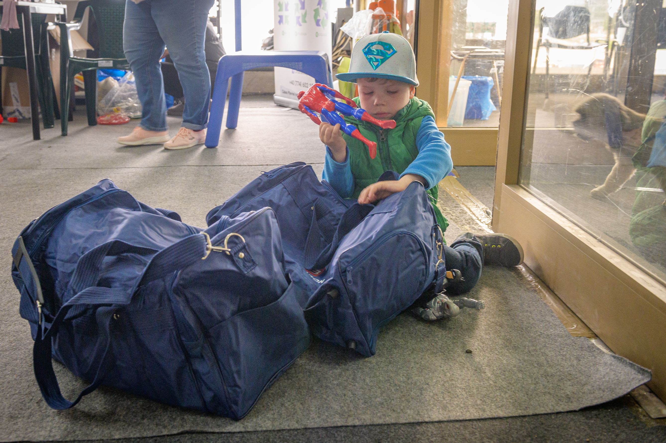 Ukrainian refugee child adds a toy to the family’s bags of supplies from RomExpo in Romania.