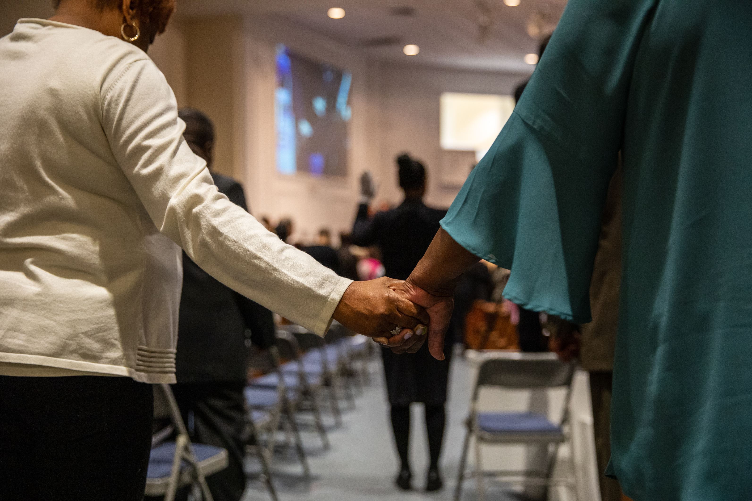 Two people hold hands in a church in the USA