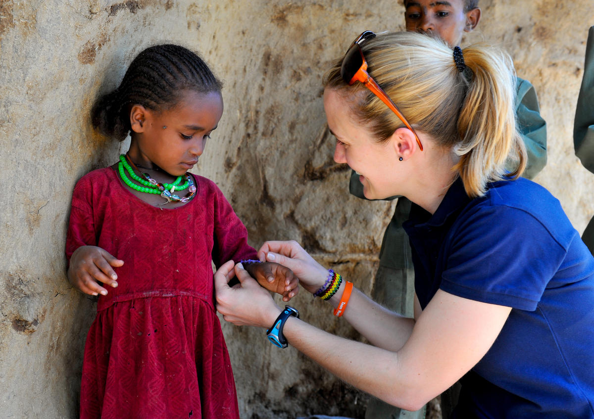 A child sponsor, gives a girl a necklace and bracelet matching her own, in Ethiopia.