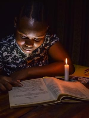 A child studying in the candle light.