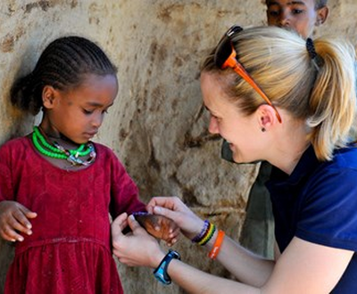 A child sponsor, gives a child a necklace and bracelet matching her own, in Ethopia