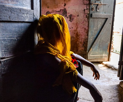 A girl looks away from the camera, her face covered in shadow as they recount her traumatic child marriage