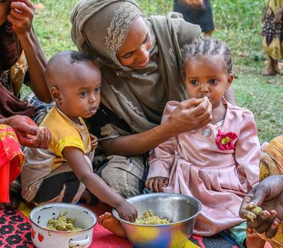 Women feed their children nutritious porridge at a World Vision Nurturing Care Group meeting in Milino Village*, Ethiopia.