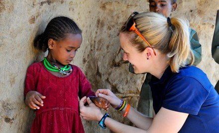 A child sponsor, gives a child a necklace and bracelet matching her own, in Ethopia
