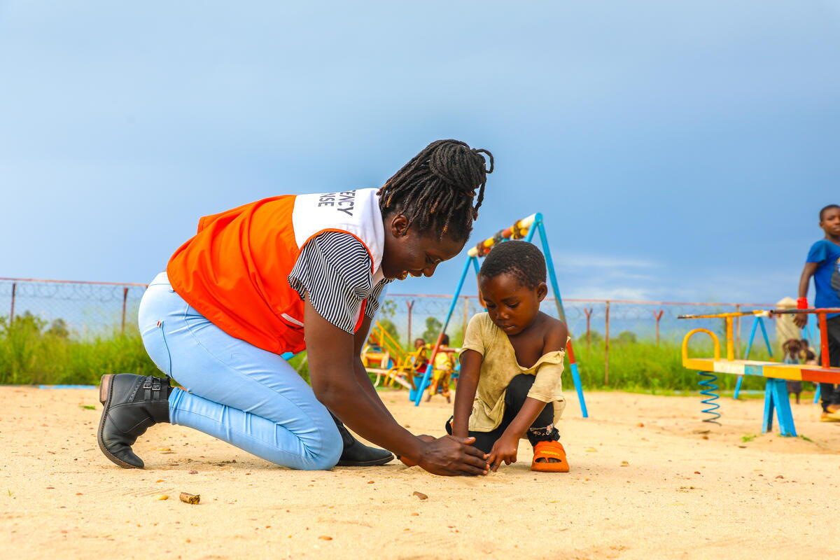 WV Project Officers playing with a child in the child-friendly space where Refugees from DRC are first received