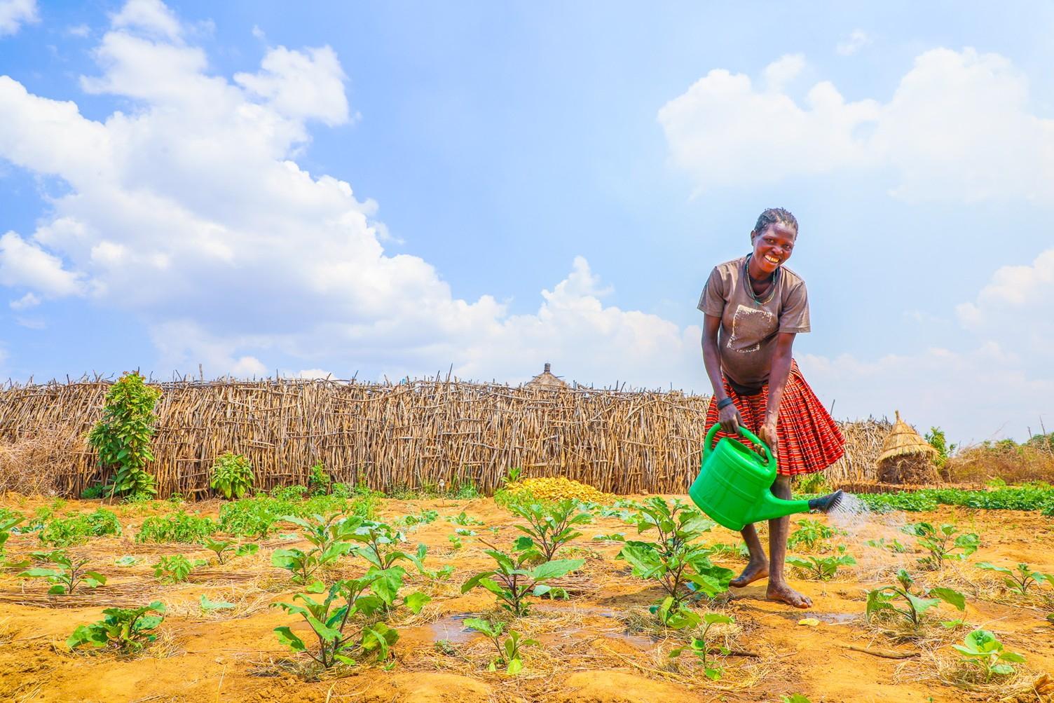 Expectant Mariah Watering her garden where she used Zai Pit technology 