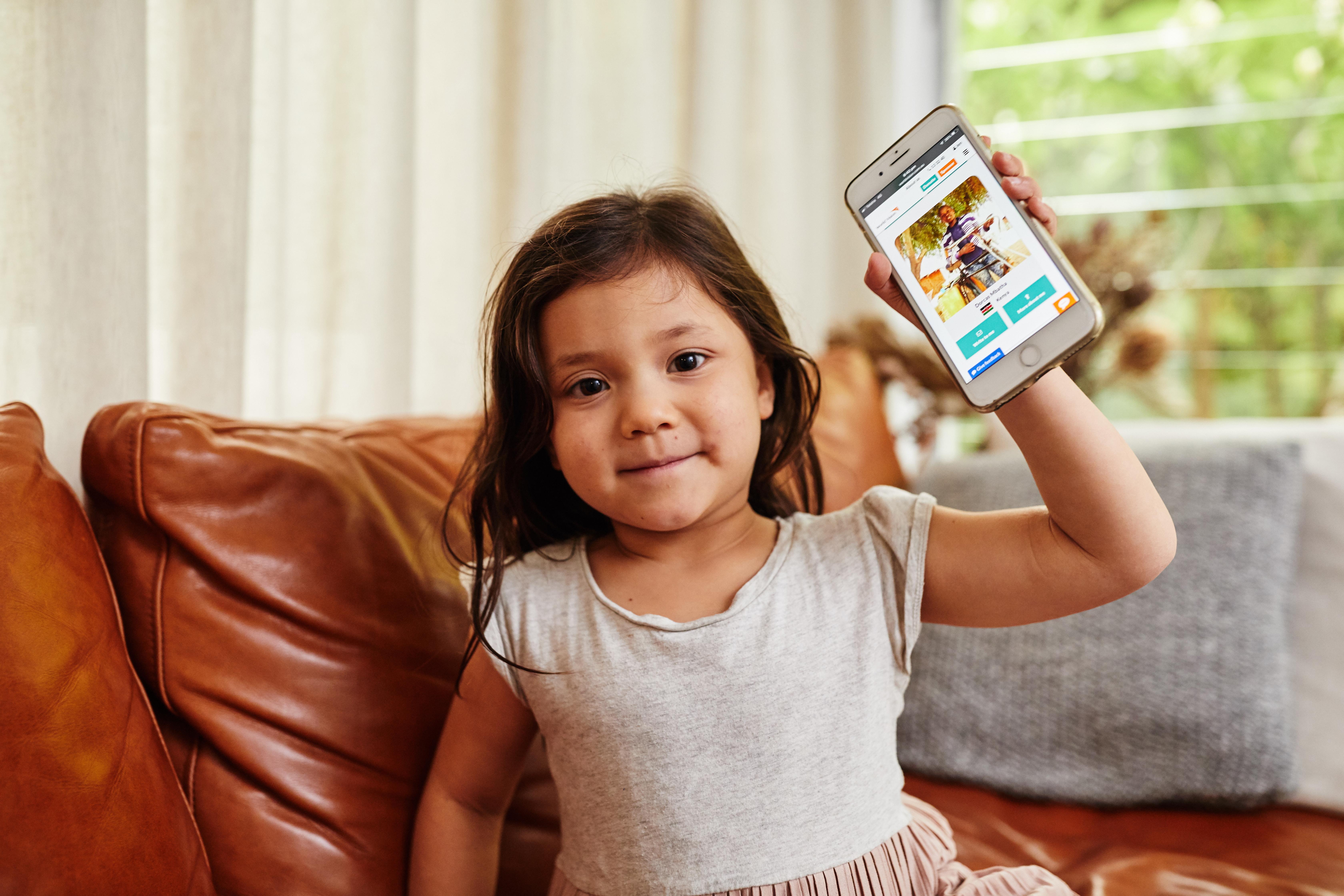 Girl child holding phone with sponsored child photo
