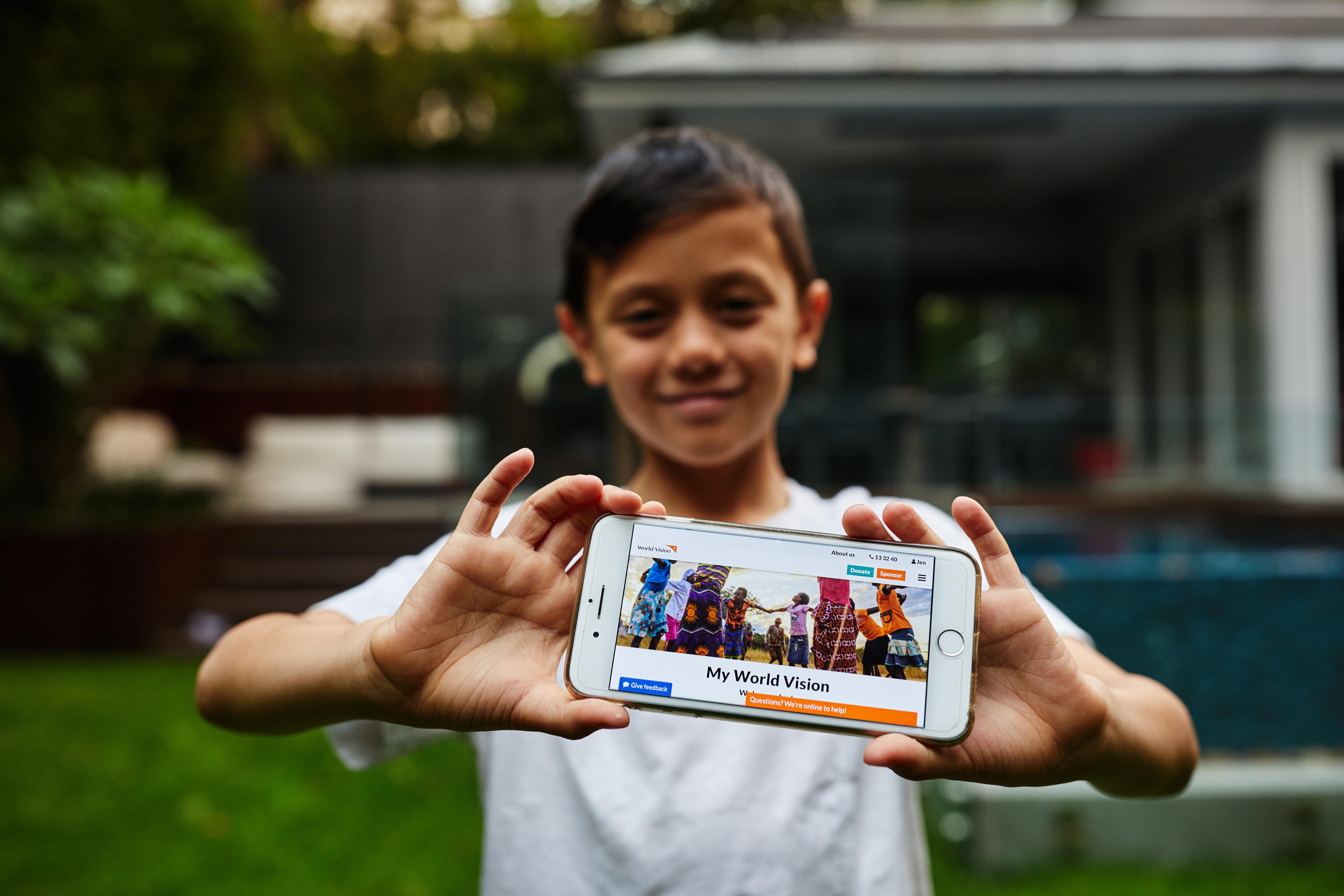 Boy holding phone with sponsored child photo