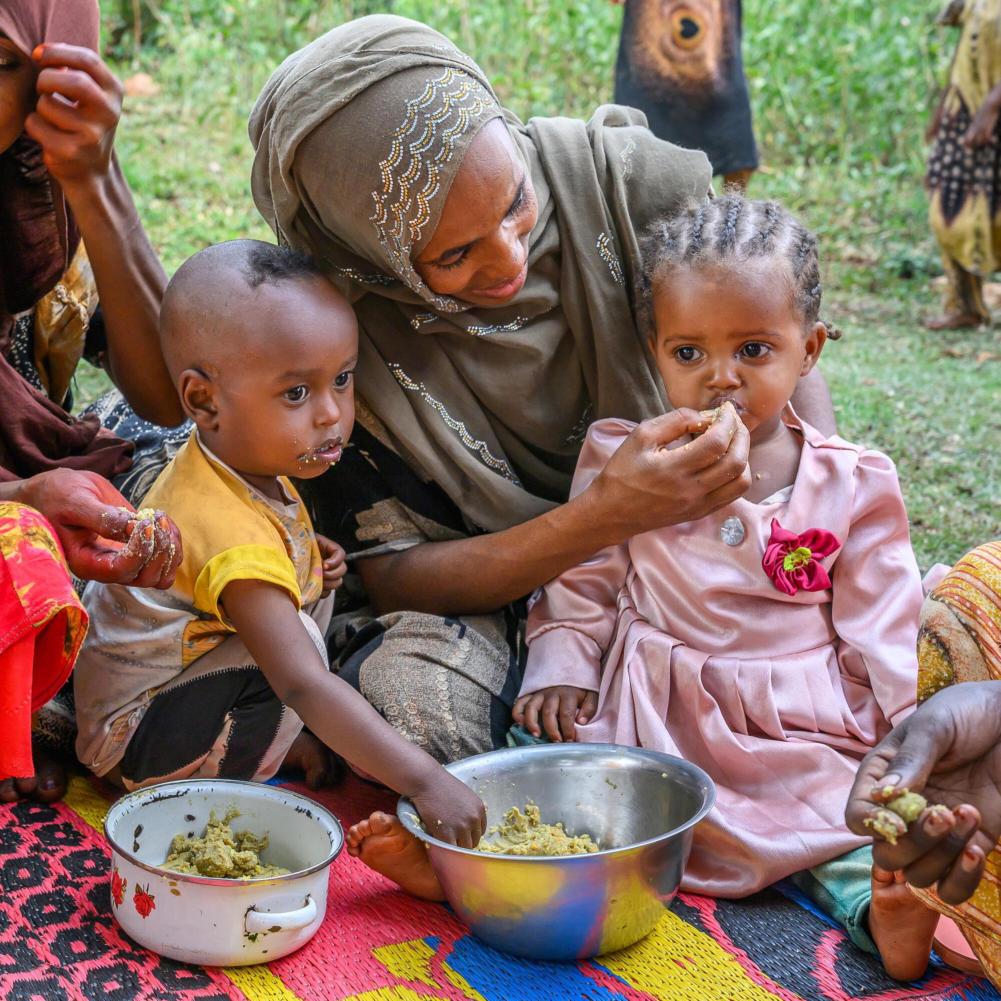 Women feed their children nutritious porridge at a World Vision Nurturing Care Group meeting in Milino Village*, Ethiopia.