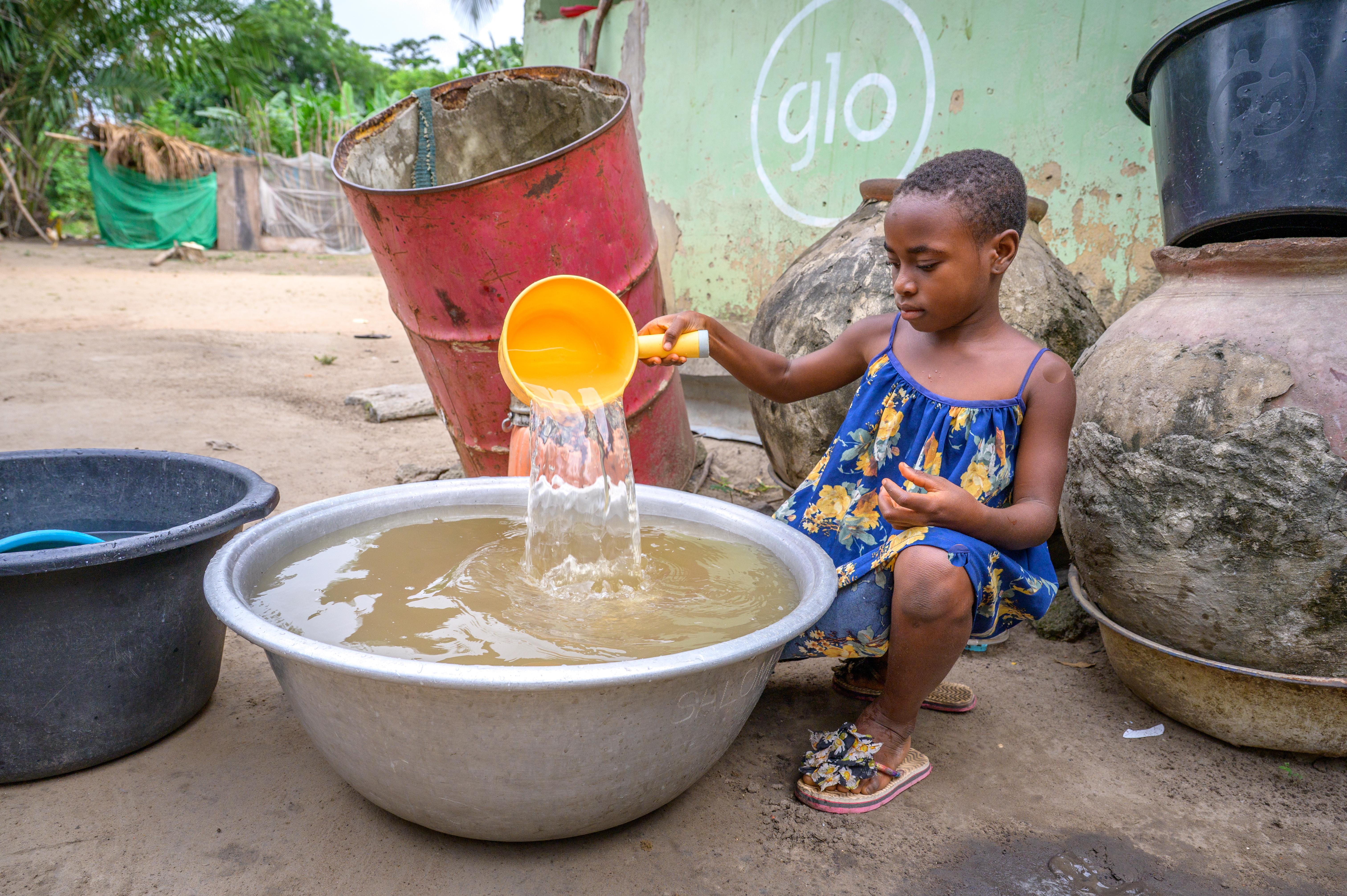 Vera scoops out the dirty water from the supply she gathered at the community water dam.