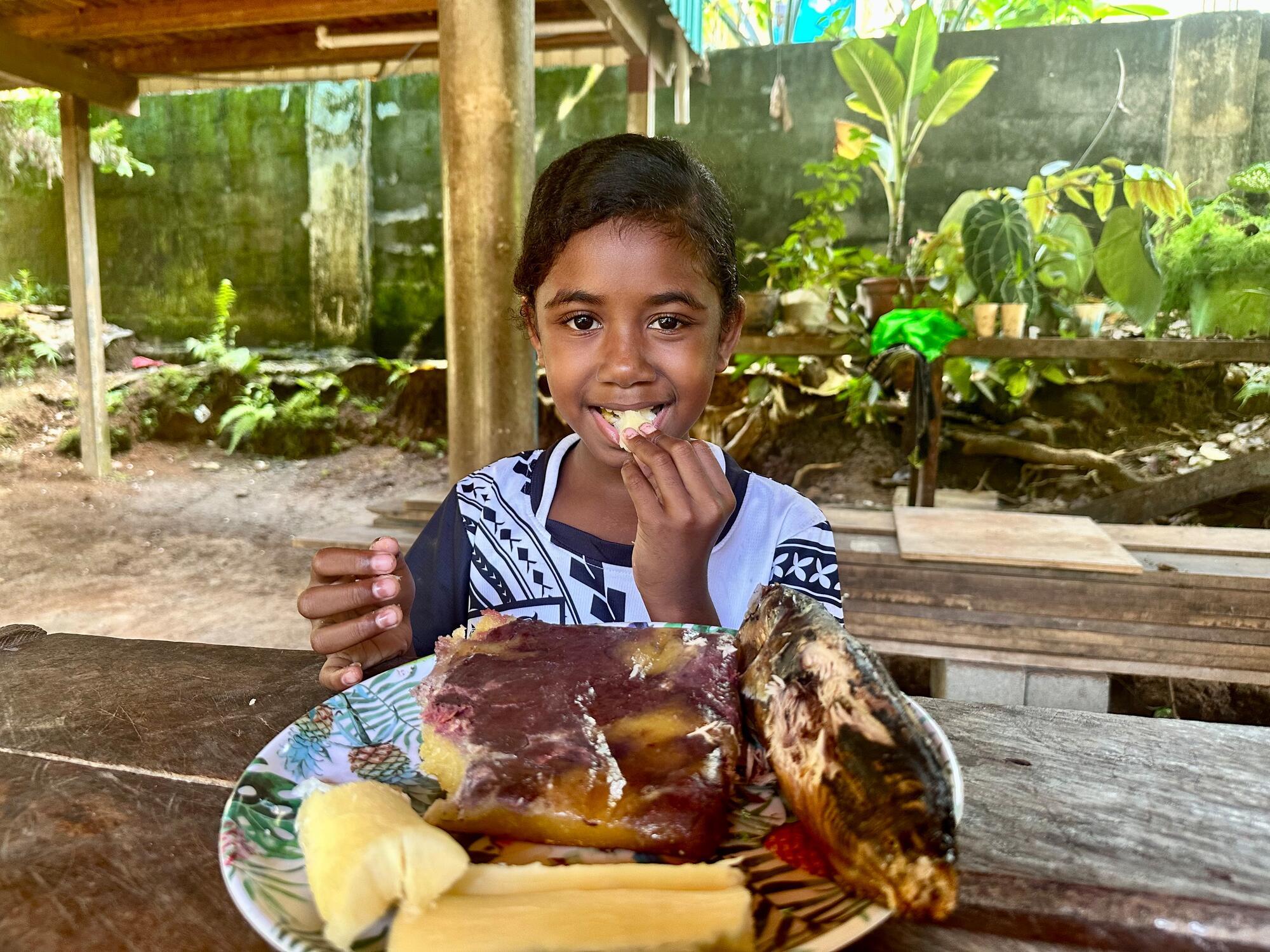 Xynah H Toiraena, a girl from the Feraladoa Community in the Solomon Islands, eating a traditional meal prepared for her.