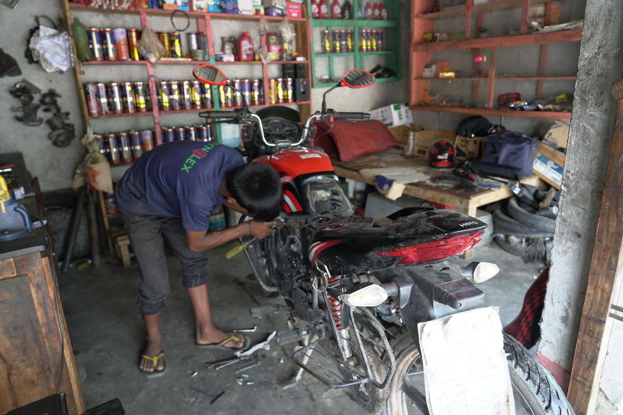 Sanjal working at a motorcycle repair shop.